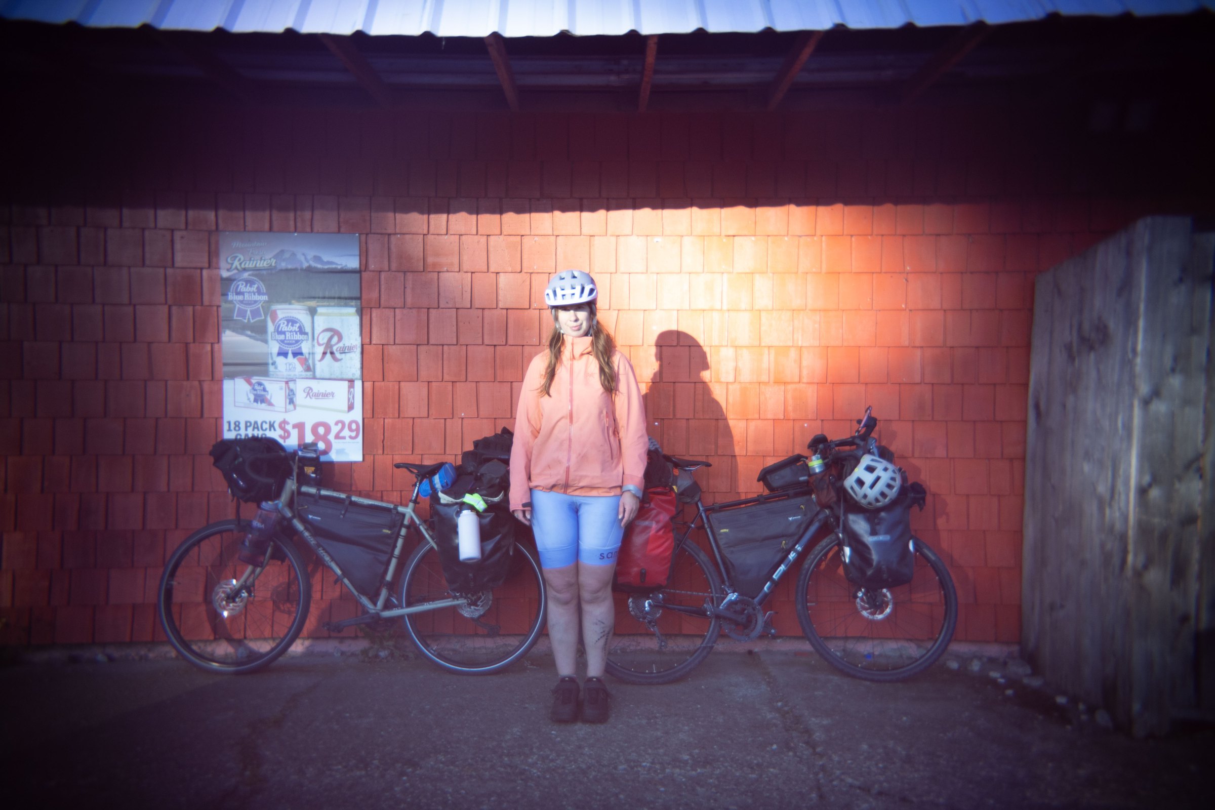 Bailey standing between two loaded touring bikes in warm evening light