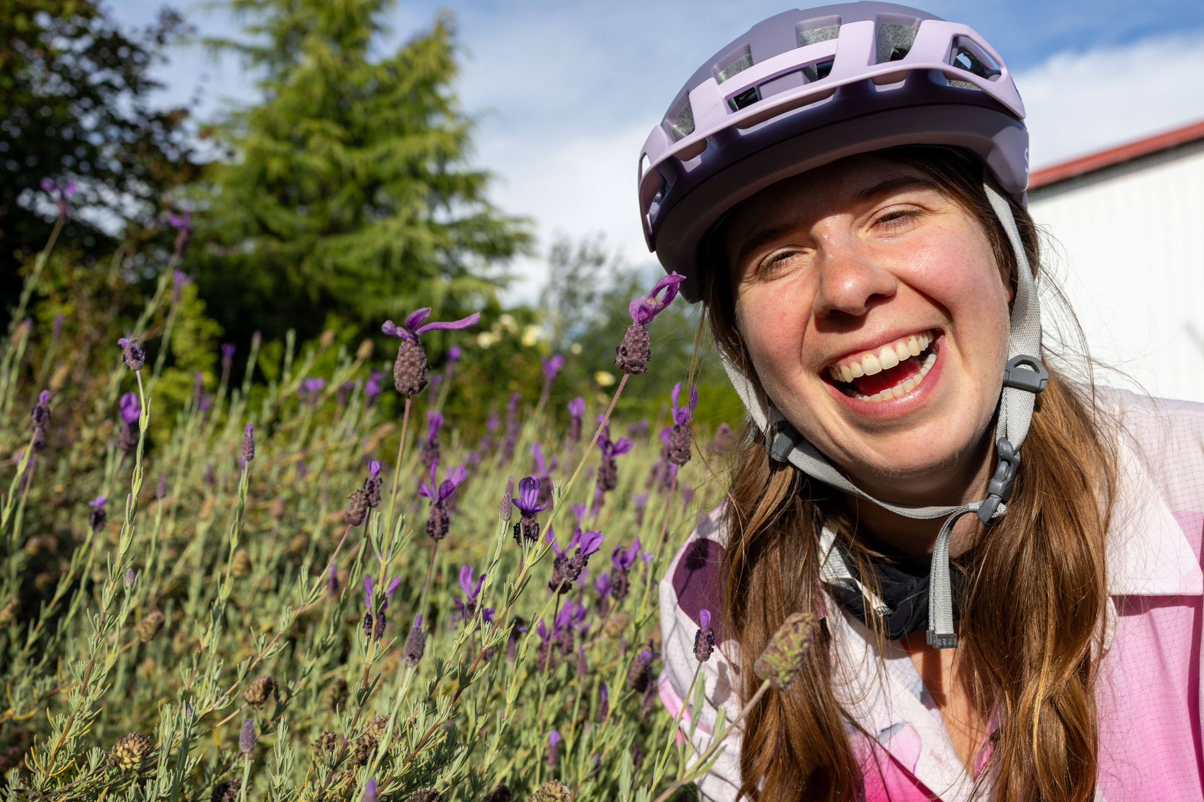 Bailey smiling beside purple lavender flowers in her cycling helmet