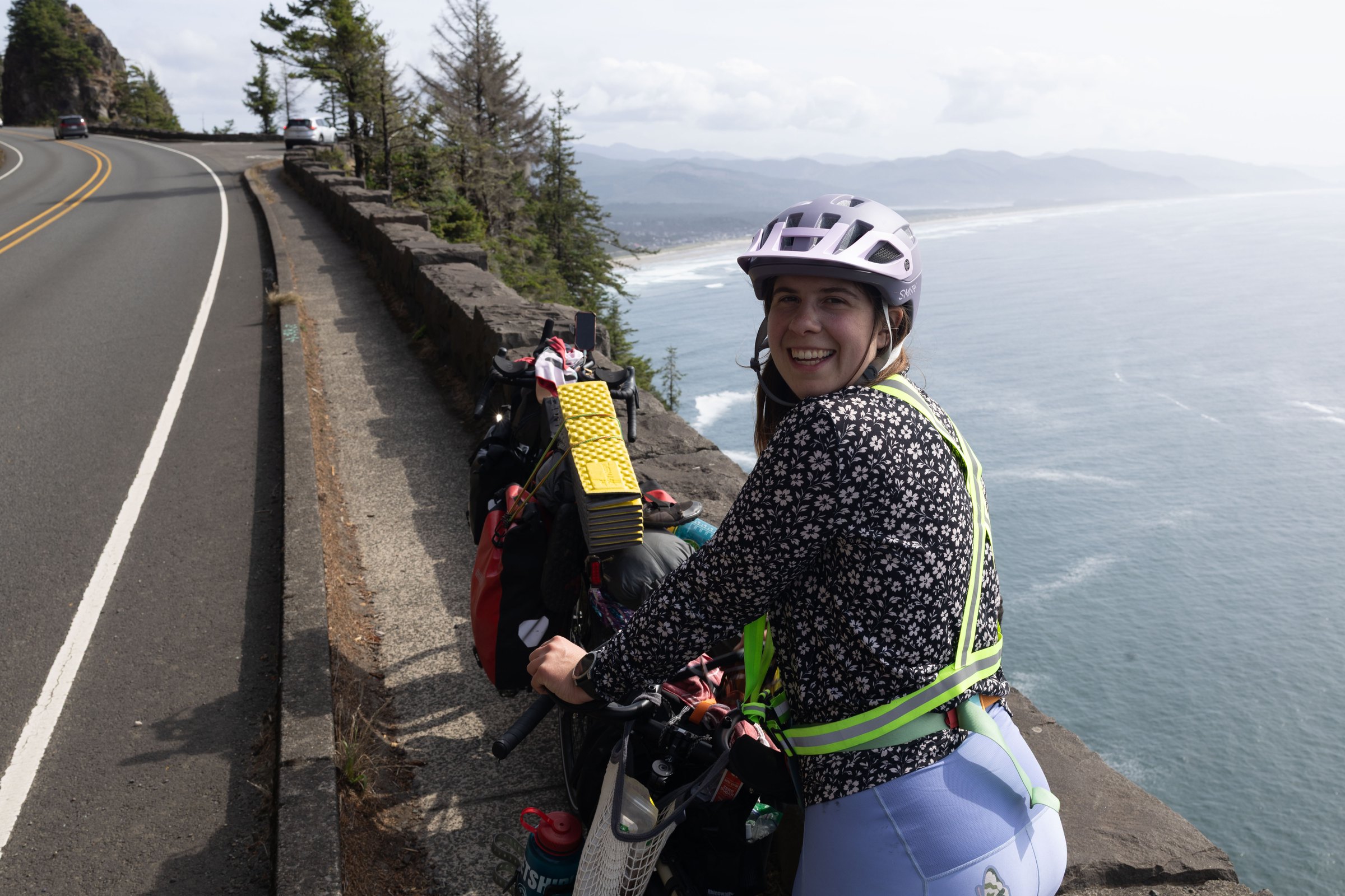 Bailey smiling with her loaded bike at an ocean overlook