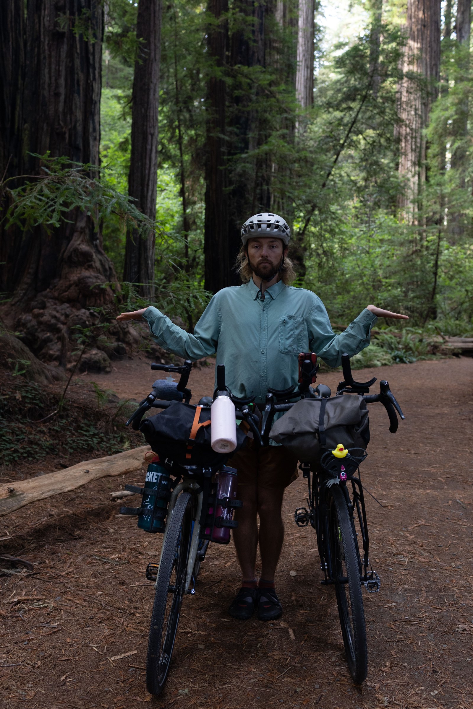 Keane standing with two touring bikes among the redwoods